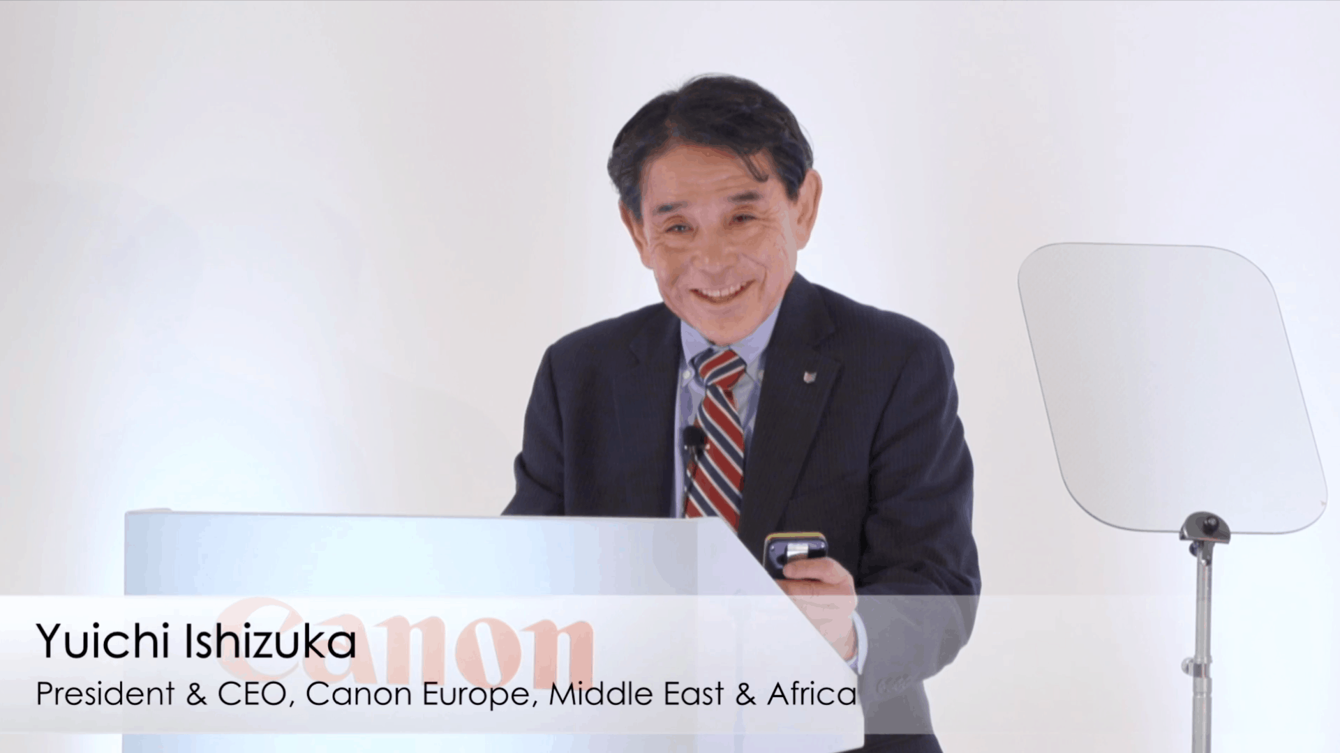 Yuichi Ishizuka, President & CEO Canon EMEA, am Pult mit Bauchbinde und Canon-Branding bei einer Veranstaltung