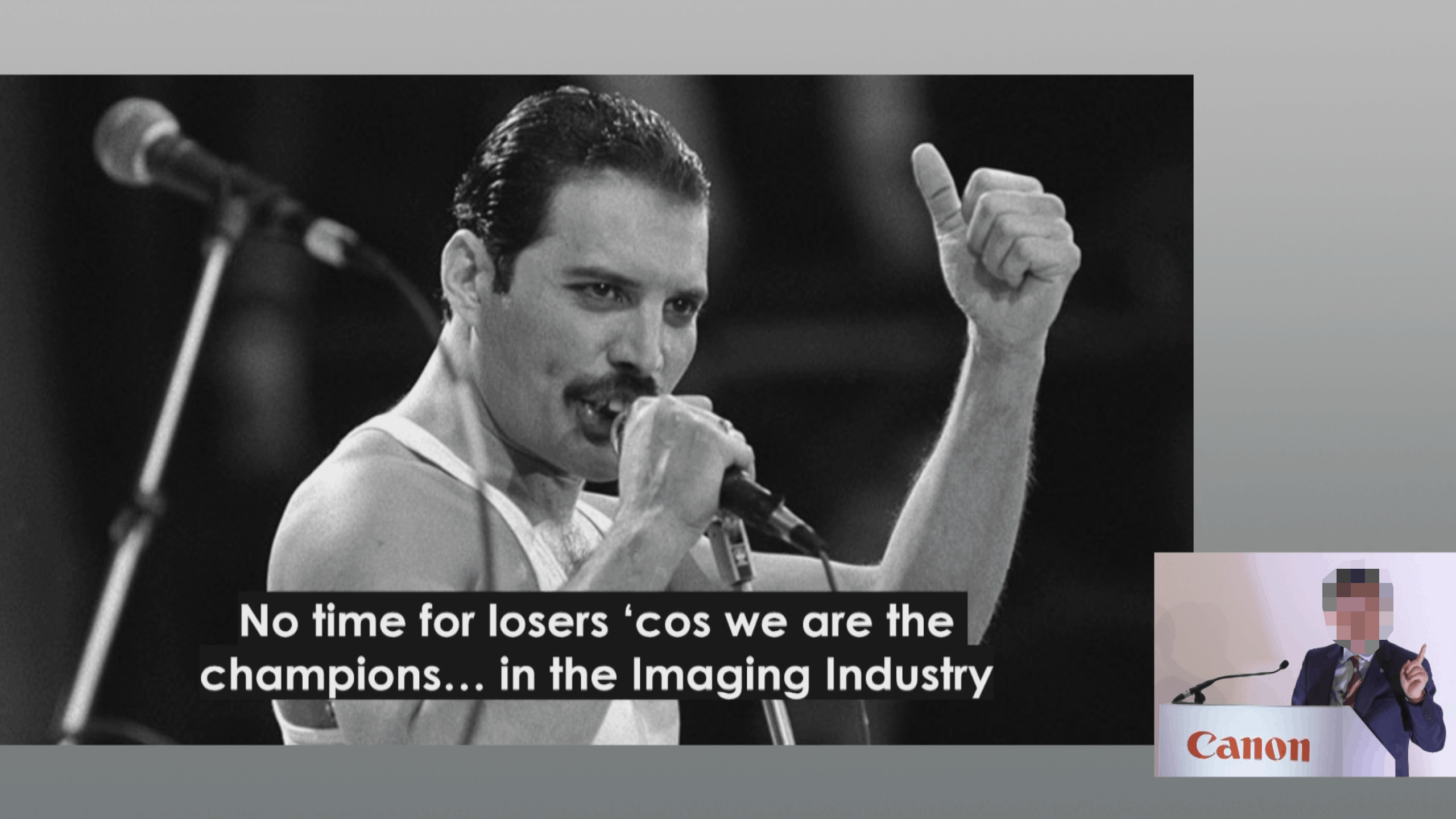 Freddie Mercury in Siegerpose mit Text 'No time for losers cos we are the champions in the Imaging Industry' und verpixeltem Canon-Sprecher am Pult