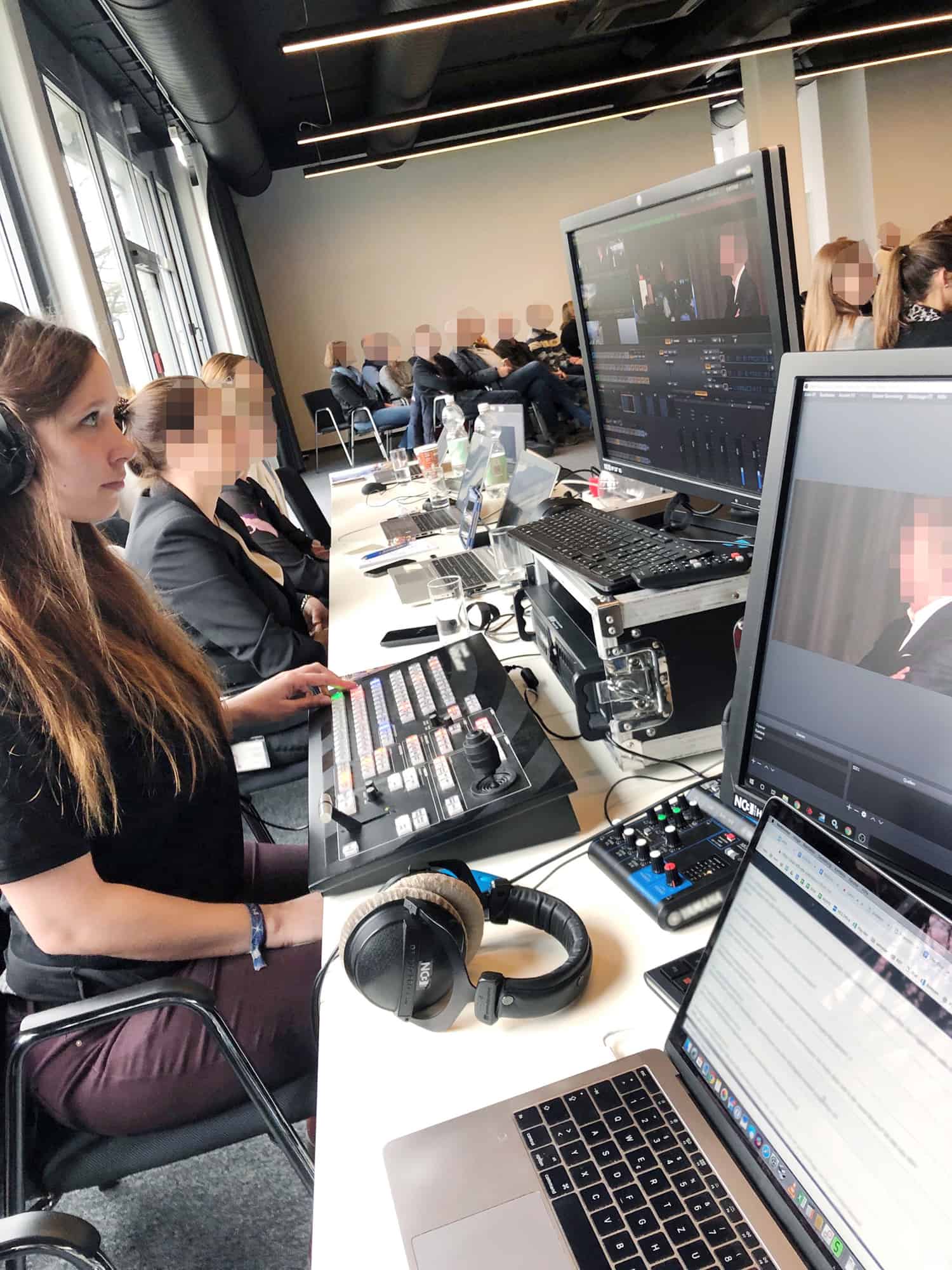 NC3-Technikerin bedient Blackmagic ATEM-Mischpult bei internem Livestream mit Publikum im Hintergrund
