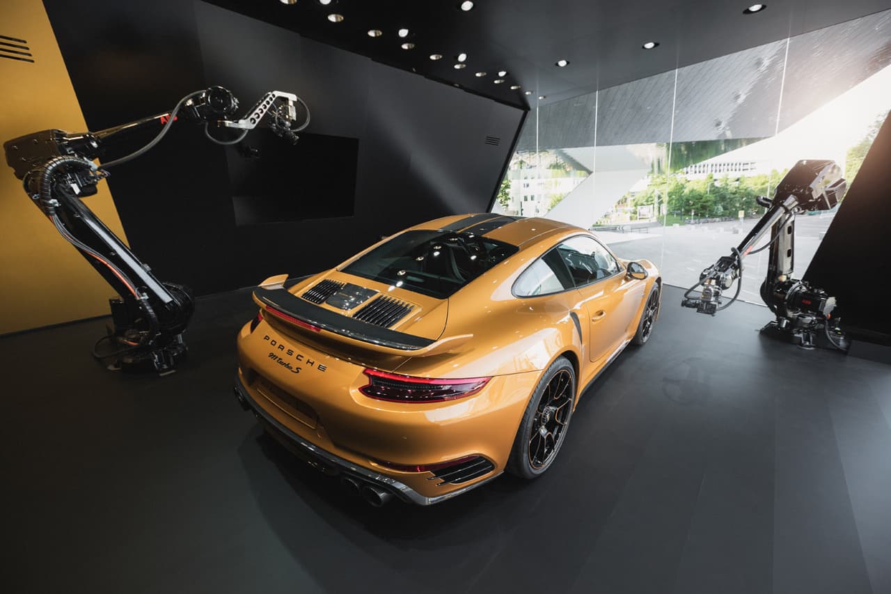 3-Cam-Livestream vom Porsche 911 3-Cam-Livestream Setup mit goldenem Porsche 911 Turbo S und zwei Roboter-Kameras in modernem Studio