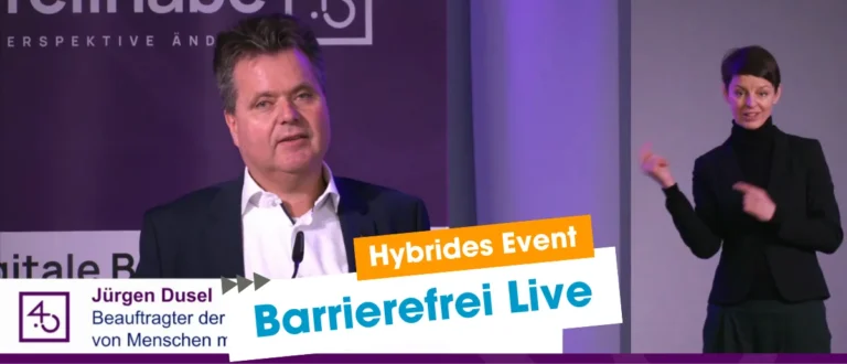 Jürgen Dusel und Gebärdensprachdolmetscherin bei barrierefreiem hybriden Event mit Live-Streaming