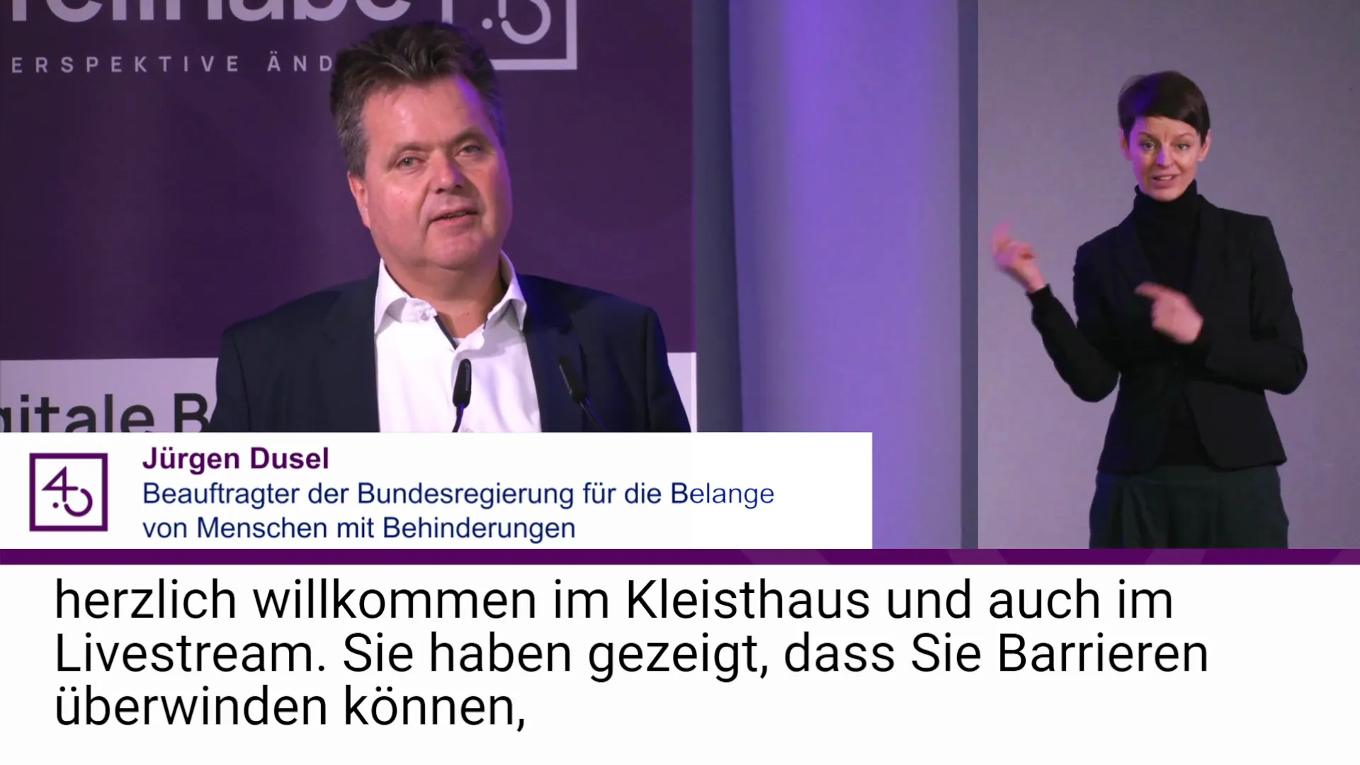 Jürgen Dusel und Gebärdensprachdolmetscherin bei barrierefreiem hybriden Event mit Live-Streaming