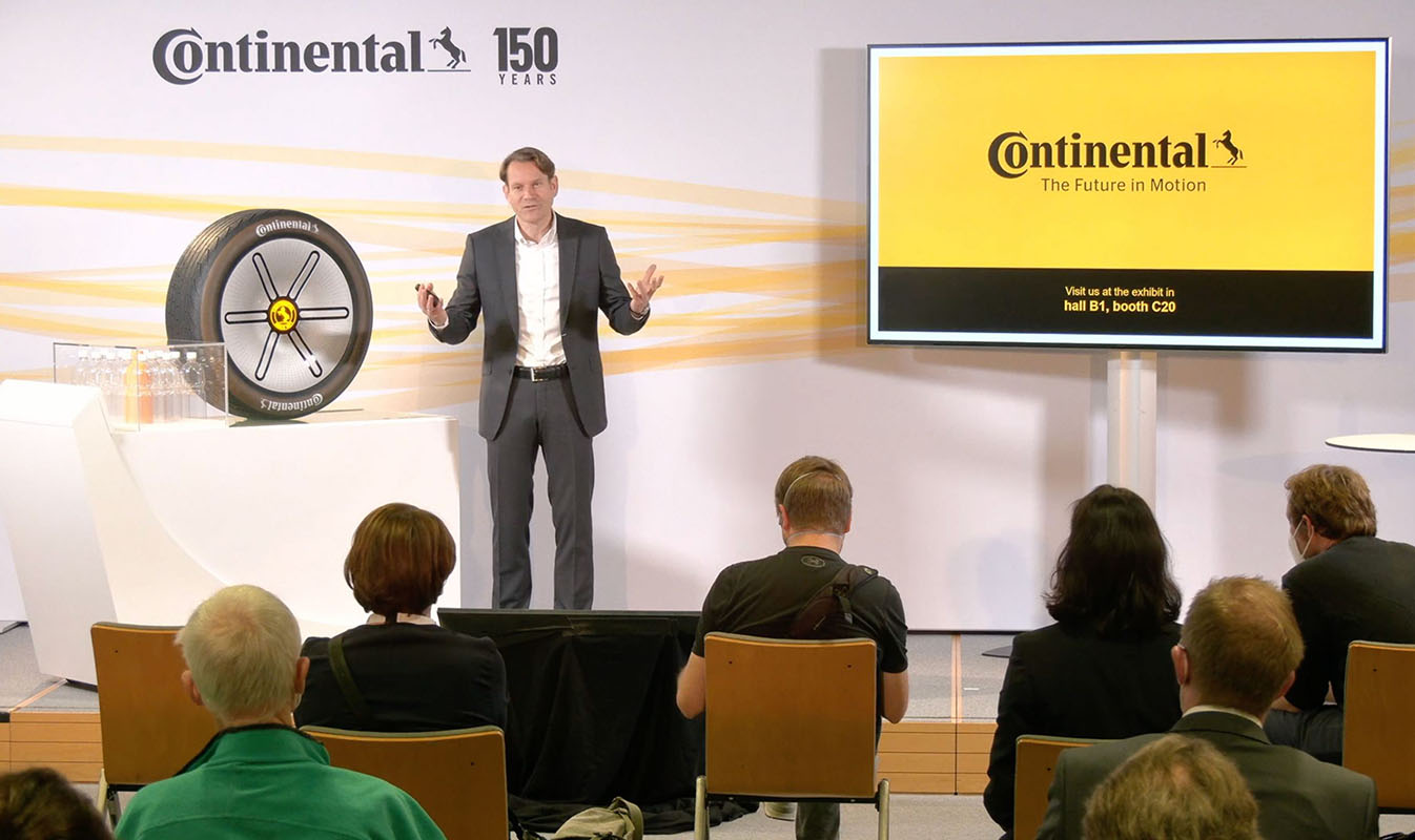 hybrides_event_digitale_veranstaltung_durchfuehren_1-scaled Redner präsentiert auf Bühne bei Continental-Konferenz mit großem LED-Screen und Publikum im hybriden Event-Setup