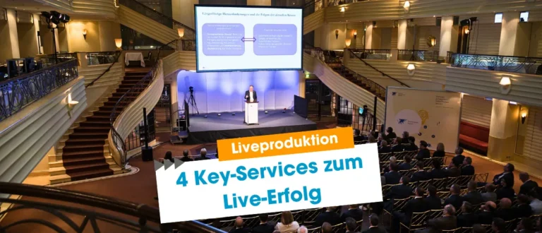 Liveproduktion im Bayerischen Hof München: Bühne mit Redner, Großleinwand, Kameras und Publikum bei professioneller Veranstaltung