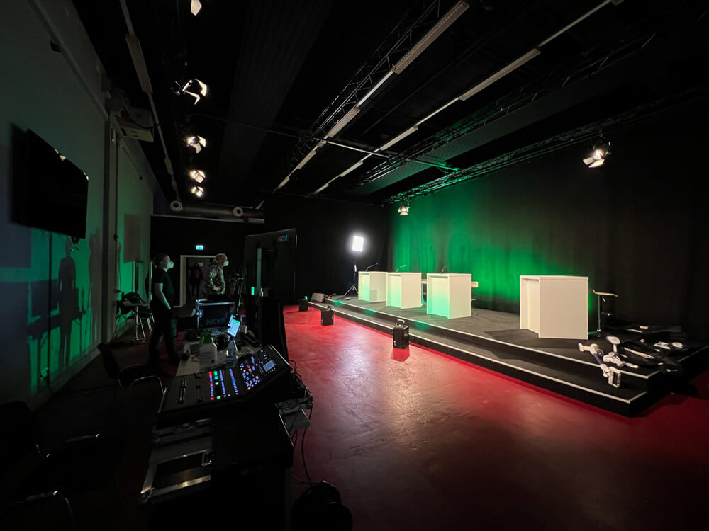 verbio-hv-studio3-ansicht-veranstaltung-live-streamen.jpg Professionelles Livestream-Studio mit beleuchteter Bühne, Regiepult und moderner Veranstaltungstechnik