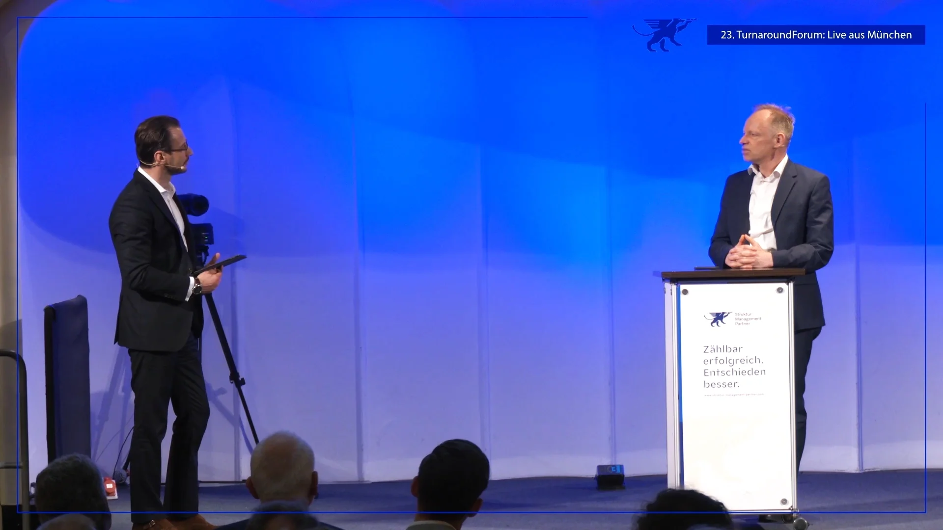 Speaker am Podium beim 23. TurnaroundForum live aus München mit Moderator und professioneller Kamera-Aufzeichnung