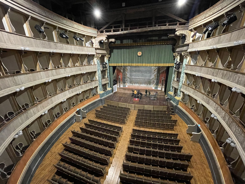 Innenansicht Teatro Sociale mit professionellem Videoproduktions-Setup: Kameras auf allen Rängen, leerer Saal und Bühne mit grünem Vorhang