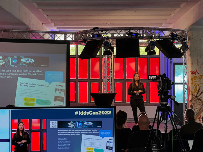 Moderatorin auf Bühne bei kidsCon2022 mit professioneller Videokamera und Bühnenbeleuchtung