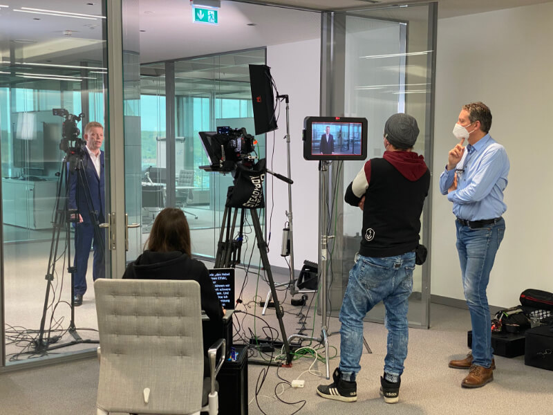 Professionelles Videoproduktionsteam bei der Aufnahme eines Unternehmensinterviews in modernem Glasbüro