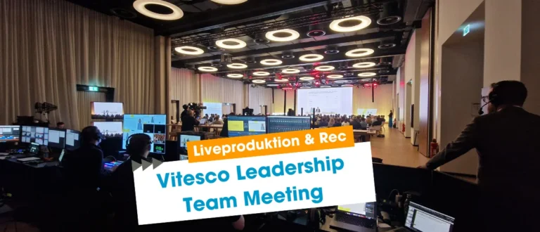 Live-Produktion des Vitesco Leadership Team Meetings: Regieraum mit Monitoren und großer Event-Saal im Hintergrund
